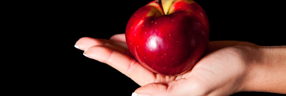 Woman holding red apple on black background